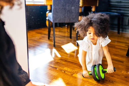 african mulatto family working out at home with children exercises with Ab Wheel absの写真素材