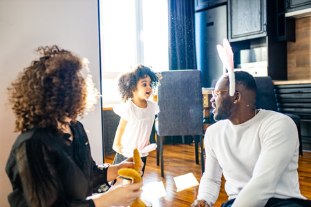 happy afro american people in bunny ears celebrate in modern big cozy houseの写真素材