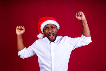 brazilian man wear santa claus headwear isolated over red color backgroundの写真素材