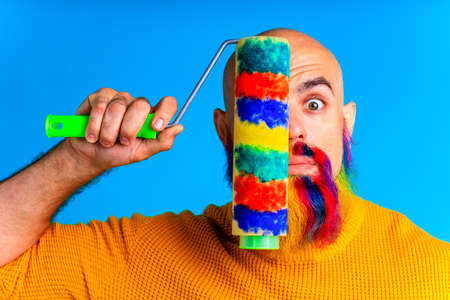 bold man paint beard in multicolors in blue studio backgroundの写真素材