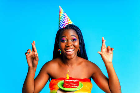 happy young woman celebrating birthday with multicolored make up and outfit over blue backgroundの写真素材