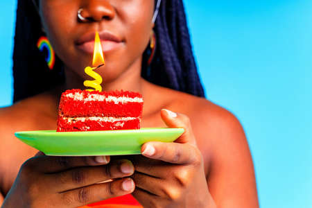 happy young woman celebrating birthday with multicolored make up and outfit over blue backgroundの写真素材