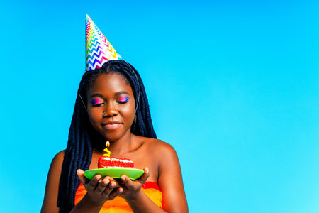 happy young woman celebrating birthday with multicolored make up and outfit over blue backgroundの写真素材