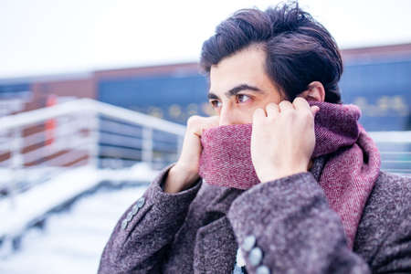 Young bearded arabian man with modern hairstyle in coat wit wool scarfの写真素材