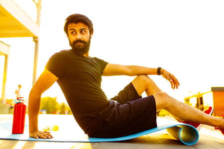 bearded man in black cotton t-shirt warming up outdoor in summer park at sunset gold lightの写真素材