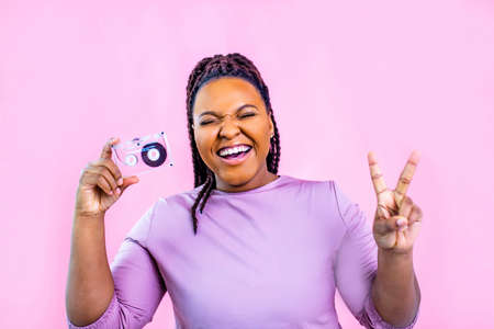 hipster lady with cool dreadlocks pigtails showing audio cassette old fashion school in pink studio...
