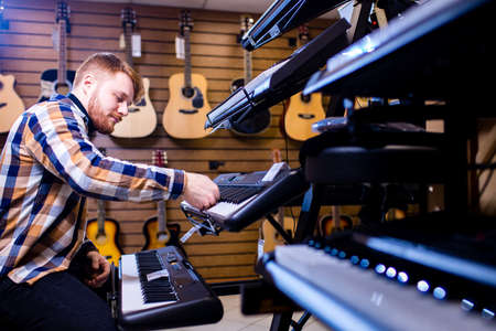 redhair ginger beard man is playing on piano in music storeの写真素材
