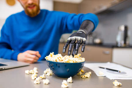 young man watching a movie in laptop and eating pop corn at home