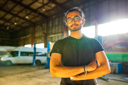 Auto mechanic standing in his workshop in sunset light backgroundの写真素材