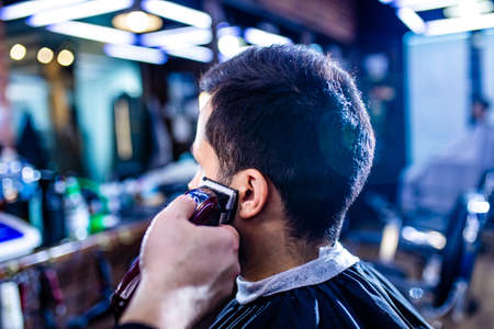 Hairstylist cutting hair of male customer at barber shopの写真素材