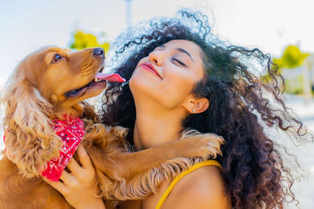 beautiful mixrd race woman with make up and curly hair style spending happy times with her cite gold american cocker dog at sunny day in the streetの写真素材