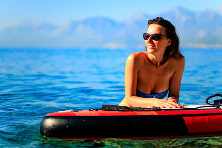 Woman sitting on sup board and enjoying peace and quiet outdoorsの写真素材