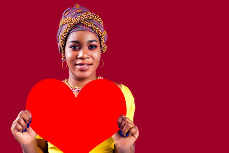 attractive lovely south woman with turban holding in hands heart isolated over red background valentines day february 14の写真素材