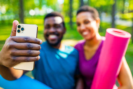latin american couple ready to yoga time outdoors pink and blue look taking self portrait on modern smartphoneの写真素材