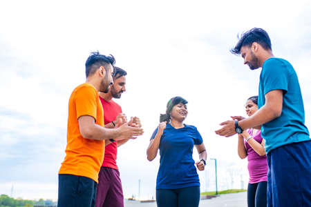 four indian people warming up outdoors in sport wear morning time urbanの写真素材