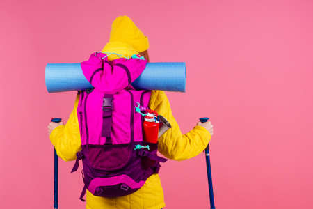 caucasian redhaired ginger woman with backpack and karemat in studio pink background. Ready for mountain adventureの写真素材