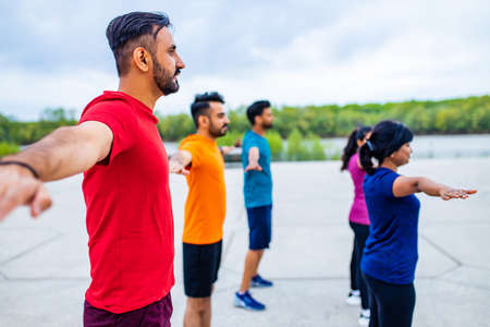 eastern ethnic people exercising together outdoor on sun lightの写真素材