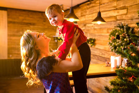 Portrait of happy mother and adorable baby celebrate Christmas in cozy kitchen