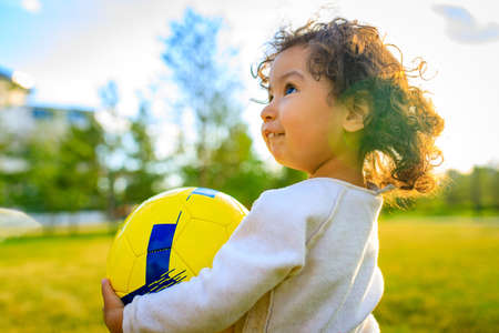 afro american little girl with curly hair playing ball outdoorsの写真素材
