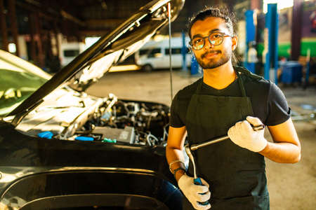 Auto mechanic standing in his workshop in sunset light backgroundの写真素材