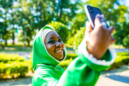 latin hispanic arab woman in green muslim dress with modern bright make up and nose piercing taking...