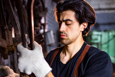 italian brunette man blacksmith working in the workshopの写真素材