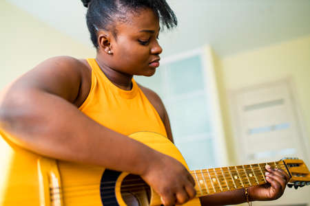 latin hispanic woman learning to play on guitarの写真素材