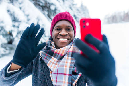 hispanic man talking by video connect by smartphone with friends of family and congratulating merry...