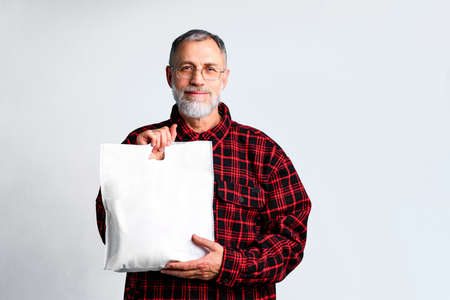 mature man is holding white textile eco bag on white backgroundの写真素材