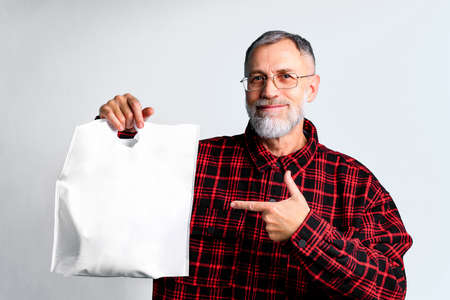 mature man is holding white textile eco bag on white backgroundの写真素材