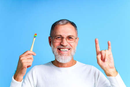 man showing multi colored rainbow tooth brush in blue background studioの写真素材