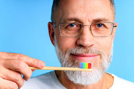 man showing multi colored rainbow tooth brush in blue background studioの写真素材