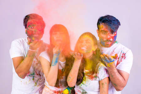 four indian students painted in colors celebrating holi festival in studio white isolate background