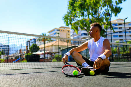 Senior caucasian man playing tennis on court holding tennis racket day light outdoors on fresh airの写真素材