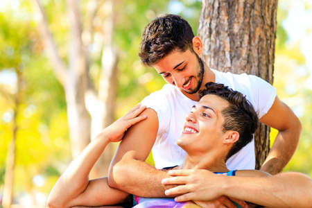 Happy gay couple spending time together in sunny day in green parkの写真素材