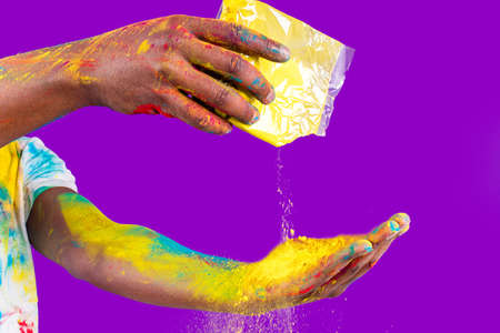 Afro american man celebrate holi festival in violet studio backgroundの写真素材