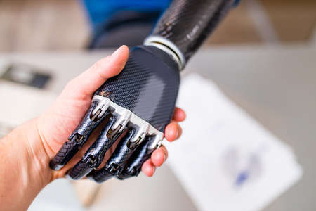 Handshake between hand of human and robot hand isolated on office backgroundの写真素材