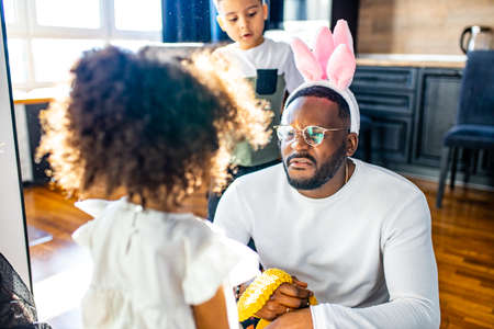 authentic ethnic multicultural people wearing bunny ears in living room day sunlightの写真素材