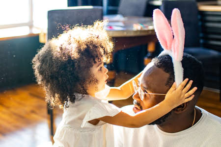 authentic ethnic multicultural people wearing bunny ears in living room day sunlightの写真素材