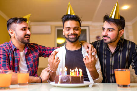 Excited arabian man ready to blow out candles on cake on birthday party with happy friends in the...