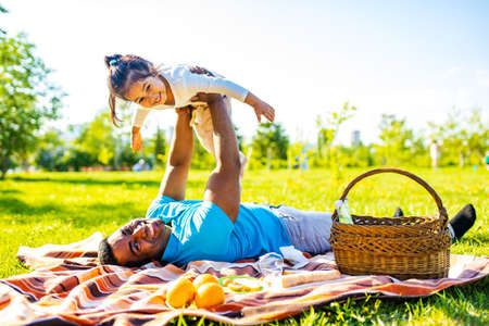 fathers day celebration happy afro american man with his cute baby in summer park having fun togetherの写真素材