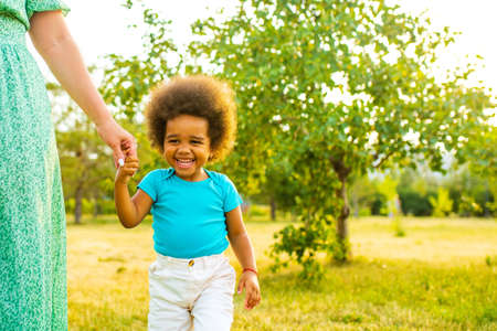african american little curly girl playing with her mother in summer park