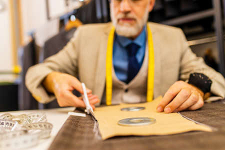 elderly good looking man in stylish and rich suit owner of atelier studio busy with workの写真素材