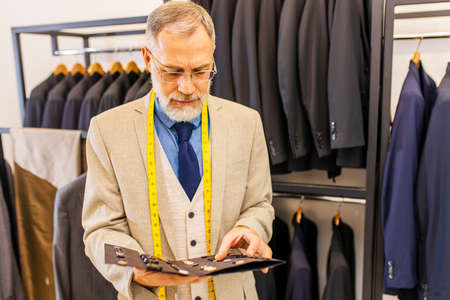 mature tailor working with sewing pattern in atelierの写真素材