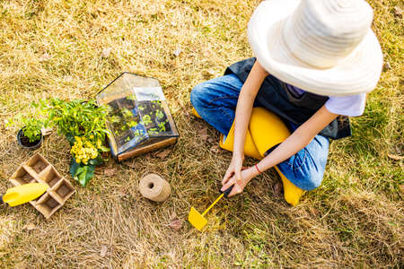 beautiful teen age girl in black apron and yellow rubber shoes in garden nature and care