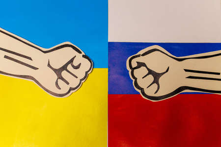 two cardboard fists on flags of Russia and Ukraine. Russian versus Ukraine trade third world war disputes and anctions policy conceptの写真素材