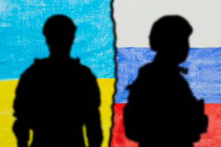 military silhouettes and flags of Russia and Ukraine painted on paper. Russian versus Ukraine trade third world war disputes and anctions policy conceptの写真素材