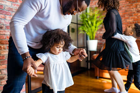 handsome brazilian male with curly hair girl are dancing in living roomの写真素材
