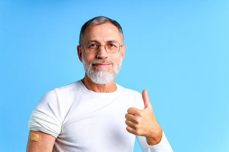 Healthy mature man getting vaccinated immunity blue background studioの写真素材