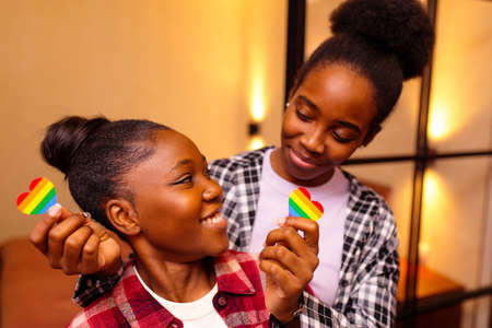 two multicultural race women with rainbow heart shape cardboard in home at eveningの写真素材